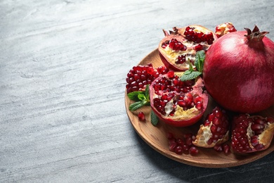 Plate with ripe pomegranates on grey background. Space for text