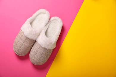 Photo of Pair of beautiful soft slippers on colorful background, top view. Space for text