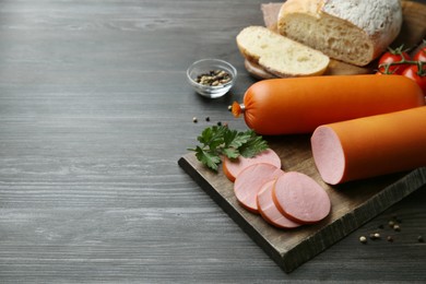 Photo of Board with tasty boiled sausages on dark wooden table. Space for text