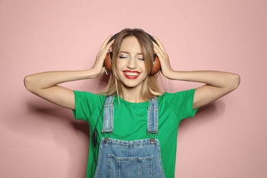 Photo of Beautiful young woman with healthy long blonde hair and headphones on color background