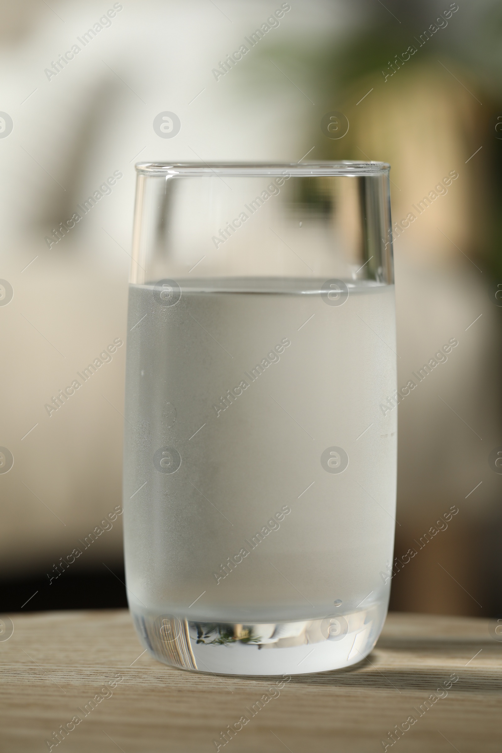 Photo of Glass of pure water on wooden table against blurred background, closeup