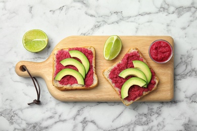 Photo of Tasty crisp toasts with avocado and chrain on wooden board, top view