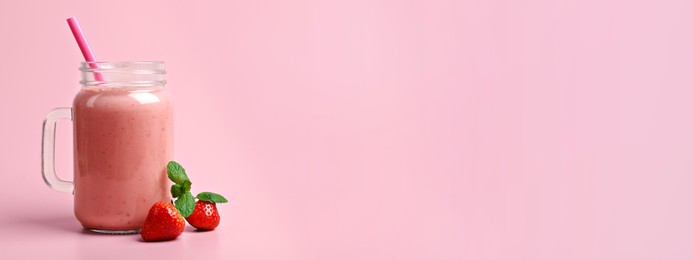 Mason jar with delicious berry smoothie and fresh strawberries on pink background, space for text. Banner design