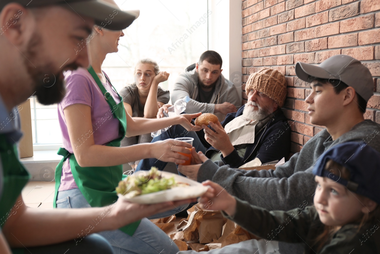 Photo of Volunteers giving food to poor people indoors