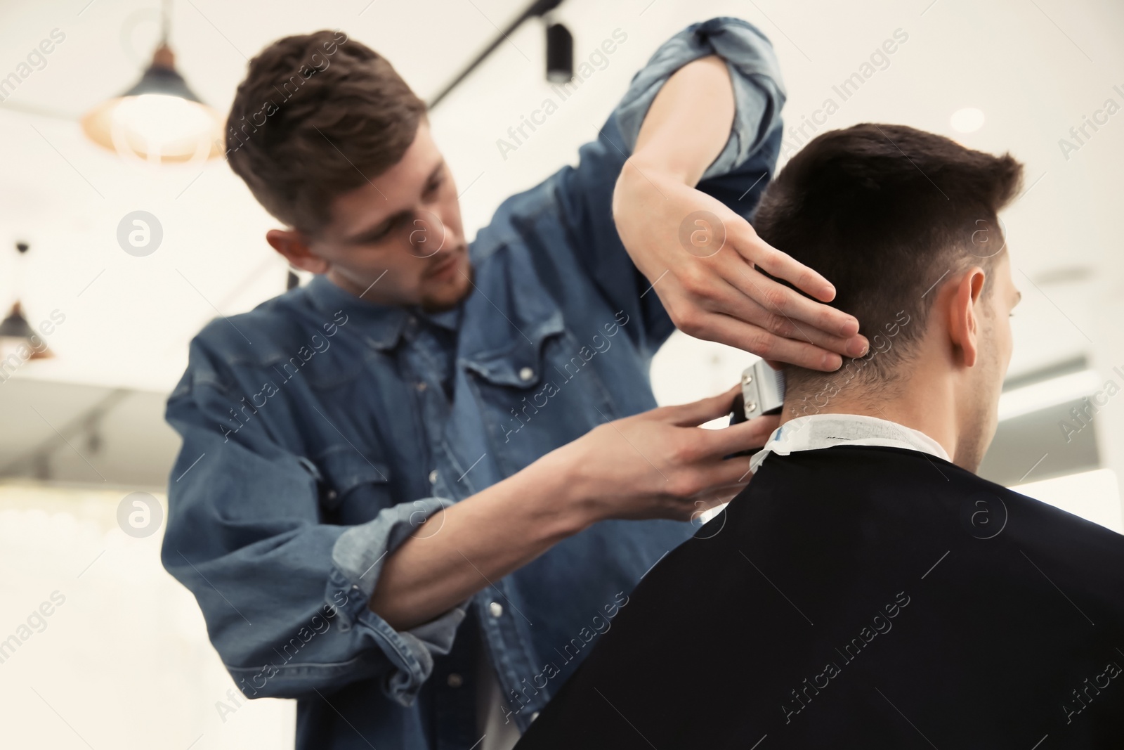 Photo of Professional barber working with client in hairdressing salon. Hipster fashion