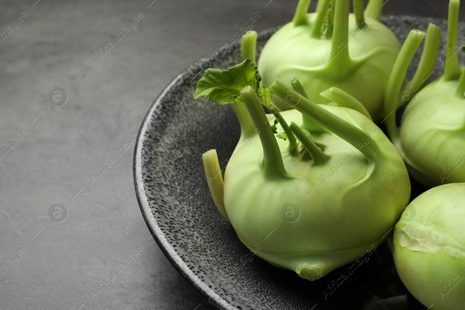 Photo of Whole ripe kohlrabi plants on grey table, closeup