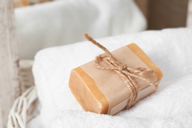 Photo of Soap bar and clean towel in laundry basket, closeup. Space for text