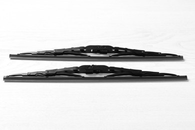 Photo of Car windshield wipers on white wooden background, flat lay