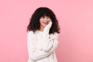 Happy young woman in stylish white sweater on pink background