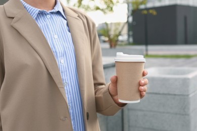 Coffee to go. Woman with paper cup of drink outdoors, closeup
