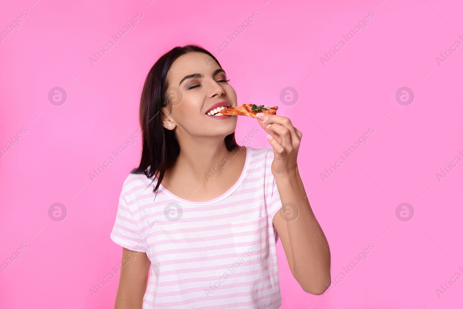 Photo of Beautiful woman eating pizza on pink background