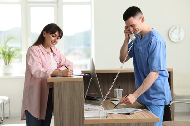 Photo of Smiling medical assistant working with patient at hospital reception