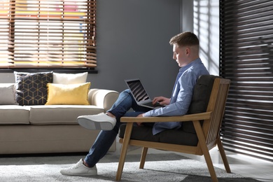 Photo of Teenage boy with laptop sitting in armchair at home