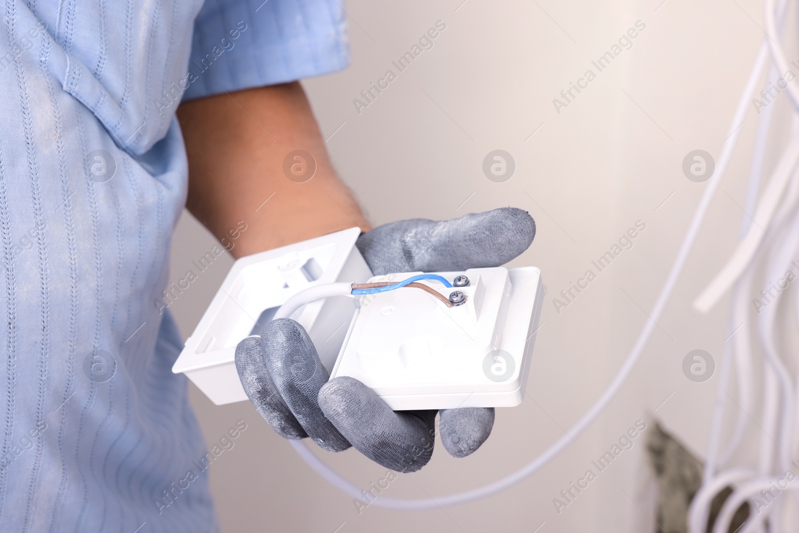 Photo of Electrician with remote meter indoors, closeup. Installation of electrical wiring