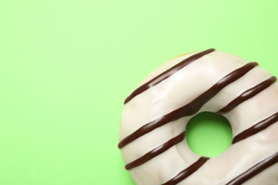 Delicious glazed donut on green background, top view. Space for text