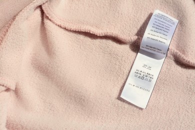 Clothing label on beige garment, closeup. Space for text