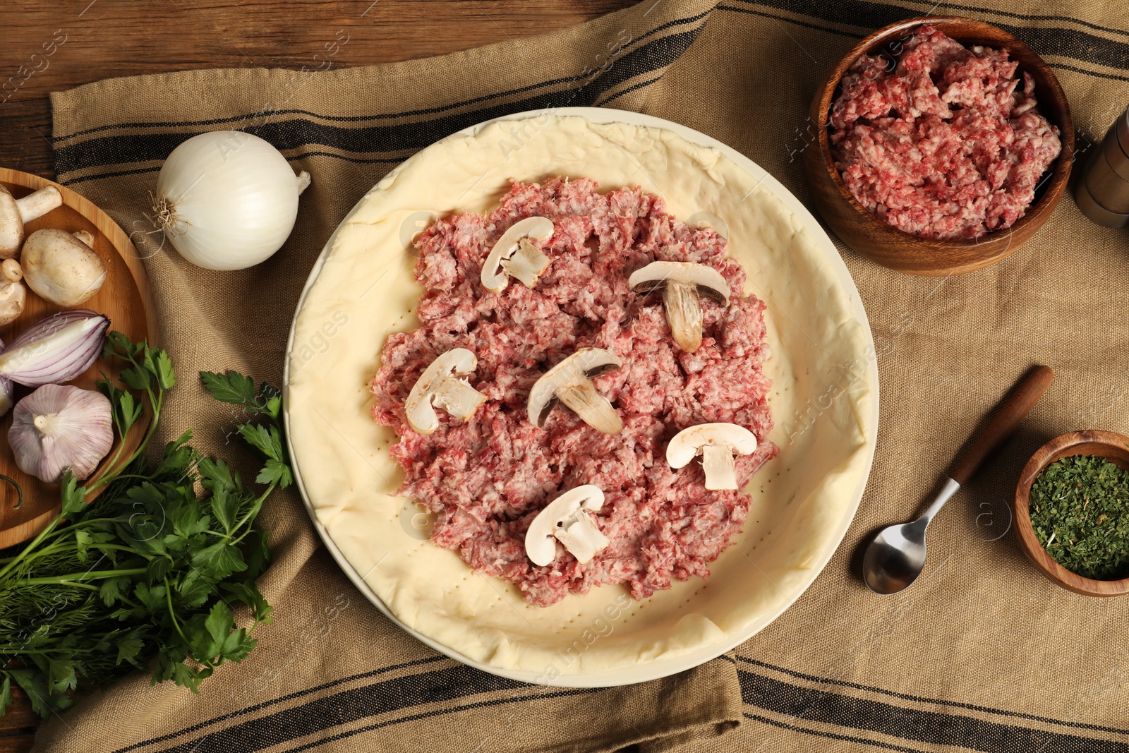 Photo of Flat lay composition with raw dough and ingredients on wooden table. Baking meat pie