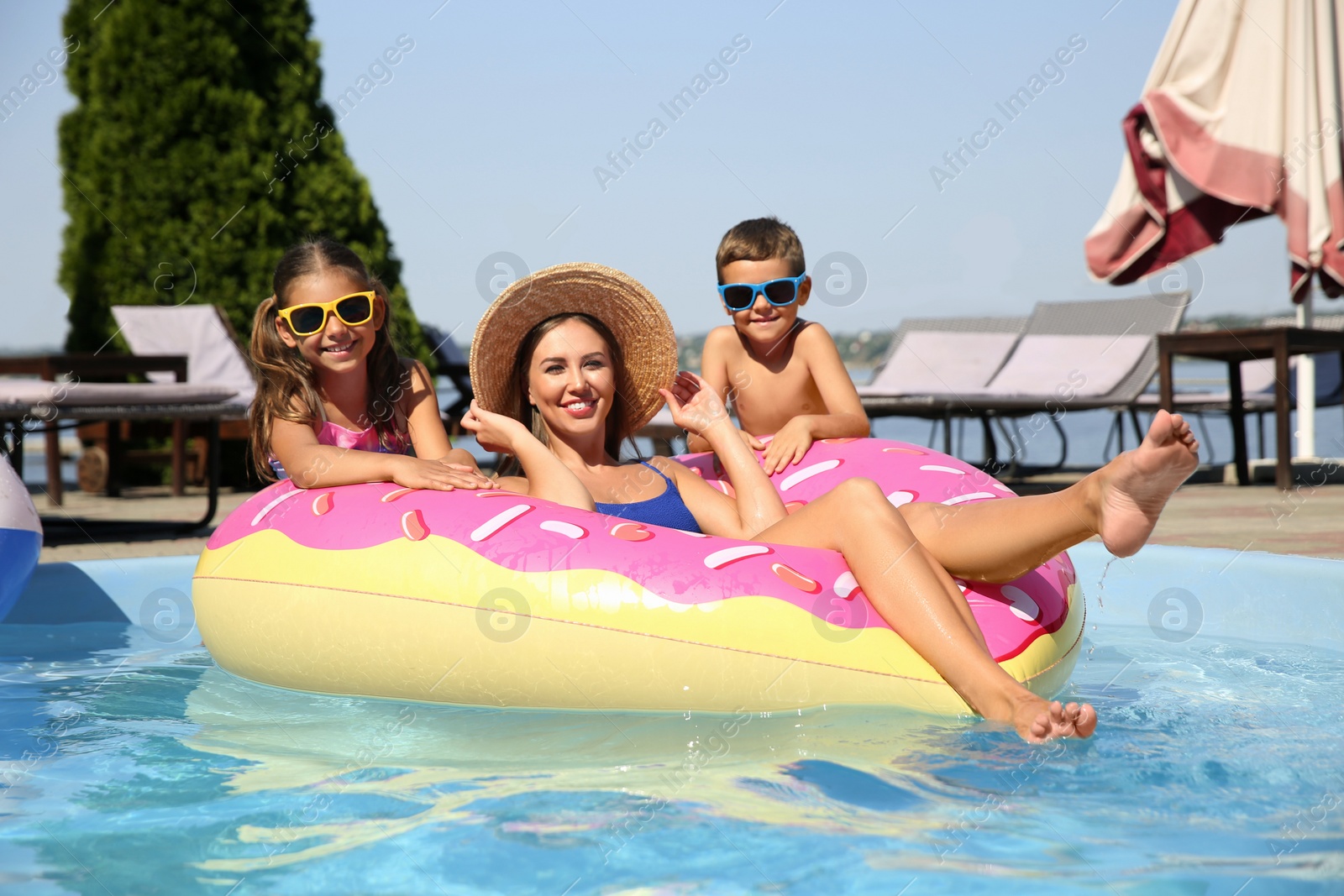 Photo of Woman with her children in swimming pool. Family vacation