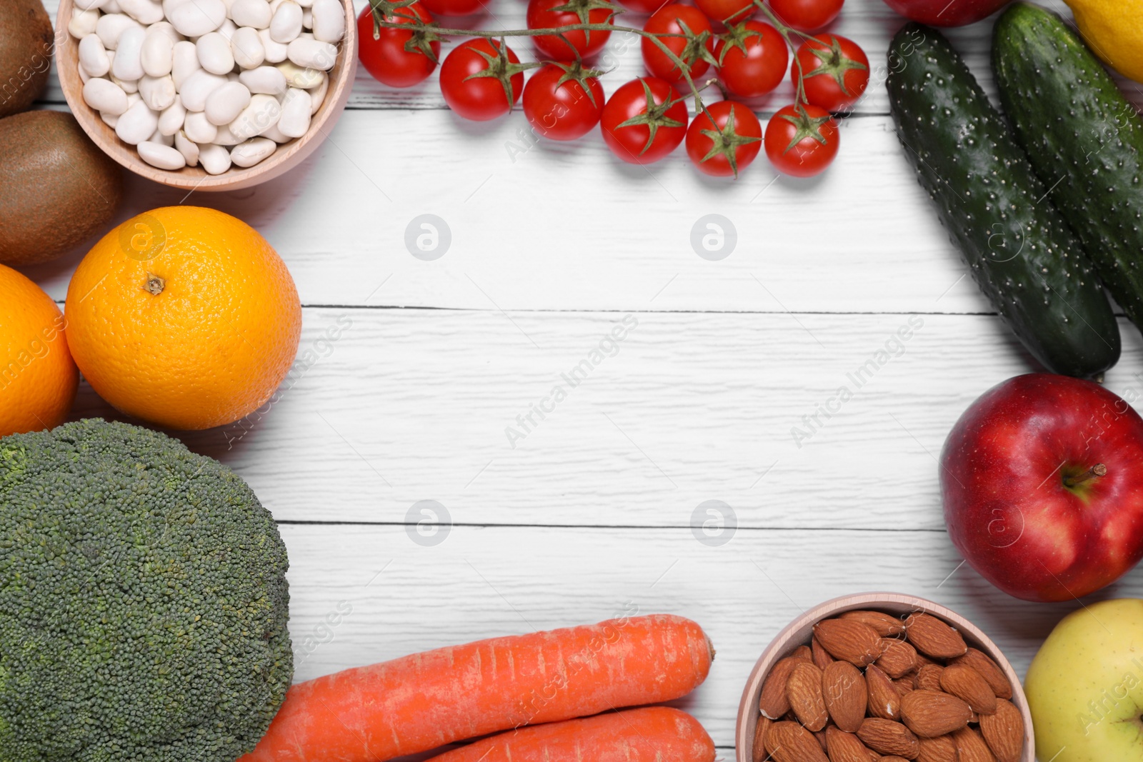 Photo of Frame of almonds, fresh fruits and vegetables on white wooden table, flat lay with space for text. Low glycemic index diet