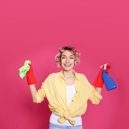 Photo of Young housewife with detergent and rag on pink background
