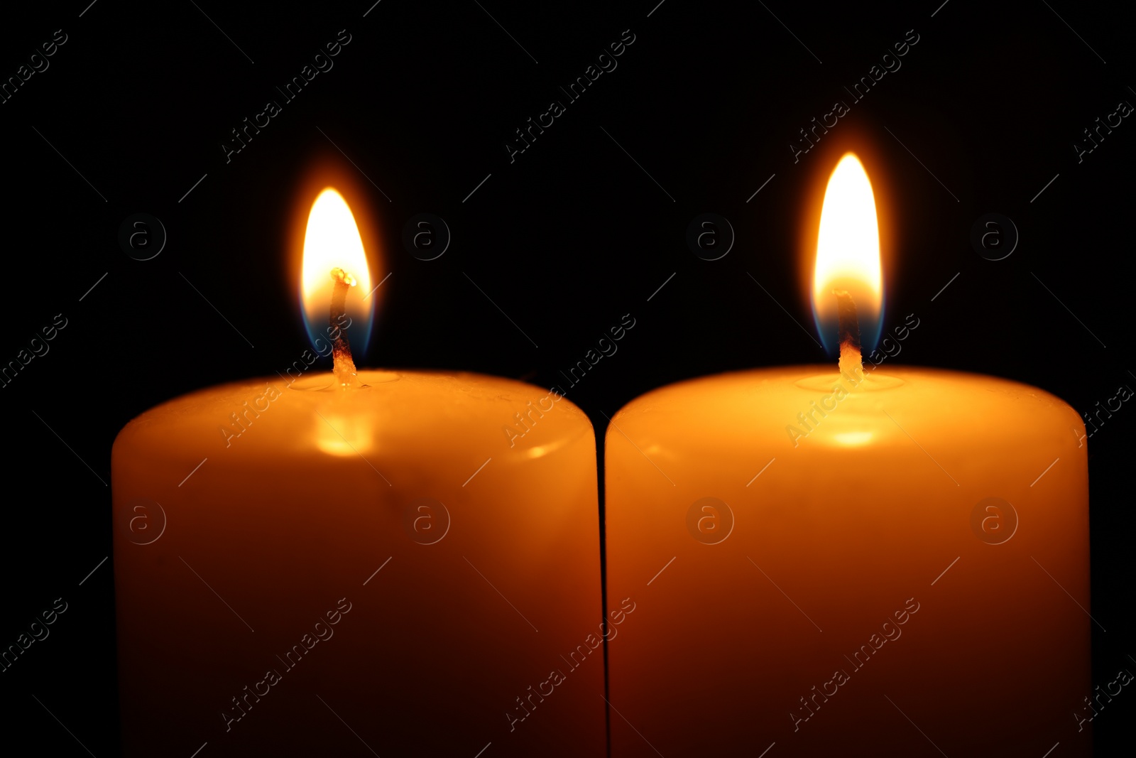 Photo of Burning wax candles on black background, closeup