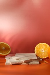 Photo of Presentation for product. Podium and tasty fresh oranges on red background, space for text