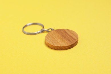 Photo of Wooden keychain in shape of smiley face on yellow background