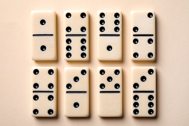 Photo of Set of classic domino tiles on beige background, flat lay