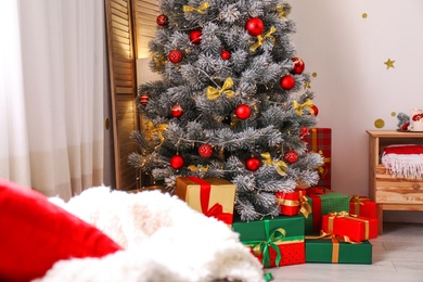 Stylish room interior with beautiful Christmas tree and gift boxes