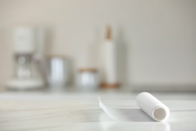 Photo of Roll of baking paper on white marble table against blurred background indoors. Space for text