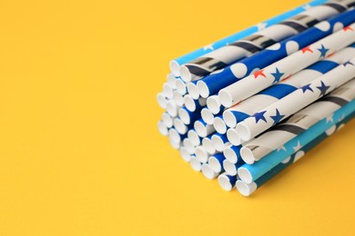 Colorful paper drinking straws on yellow background, closeup. Space for text