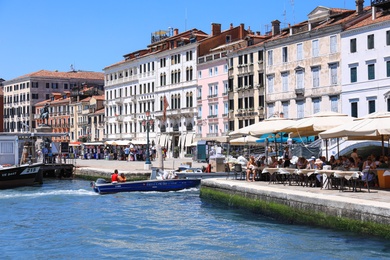 VENICE, ITALY - JUNE 13, 2019: View of city street with cafe on embankment