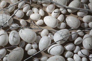 Photo of Many painted Easter eggs and tree twigs on grey background, flat lay