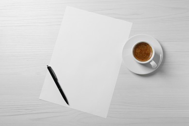 Blank paper sheet, pen and cup of coffee on white wooden table, flat lay. Space for text