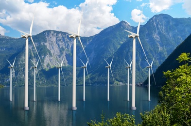 Image of Floating wind turbines installed in water near mountains. Alternative energy source