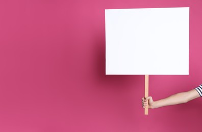 Photo of Woman holding blank sign on pink background, closeup. Space for text