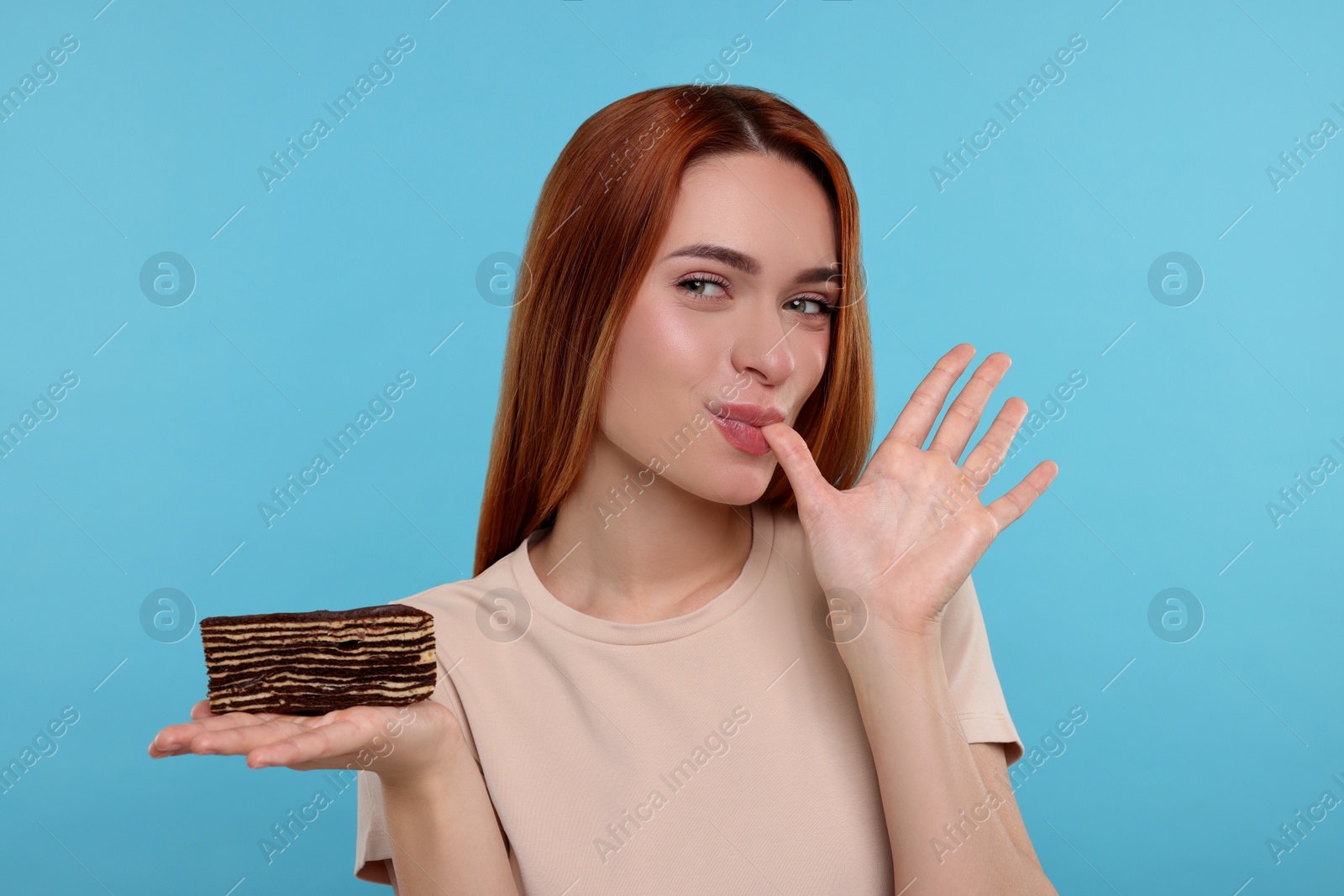 Photo of Young woman with tasty cake on light blue background