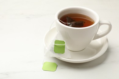 Tea bag in cup on white table, space for text