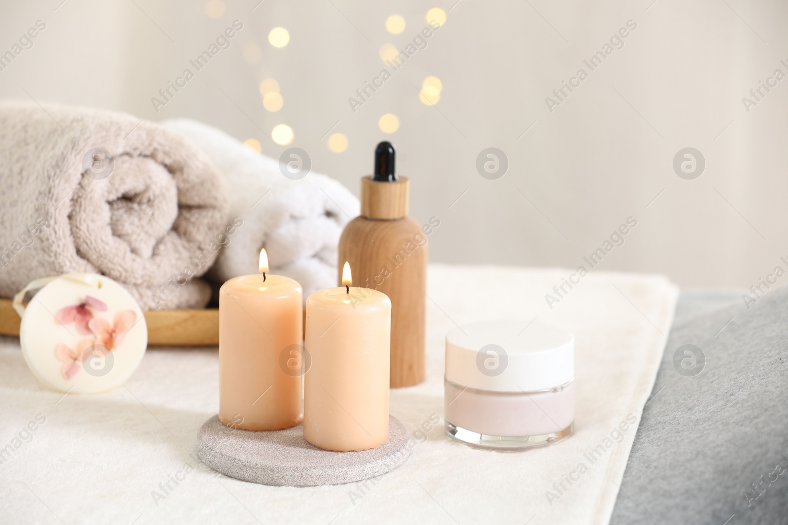 Photo of Spa composition. Burning candles and personal care products on soft surface