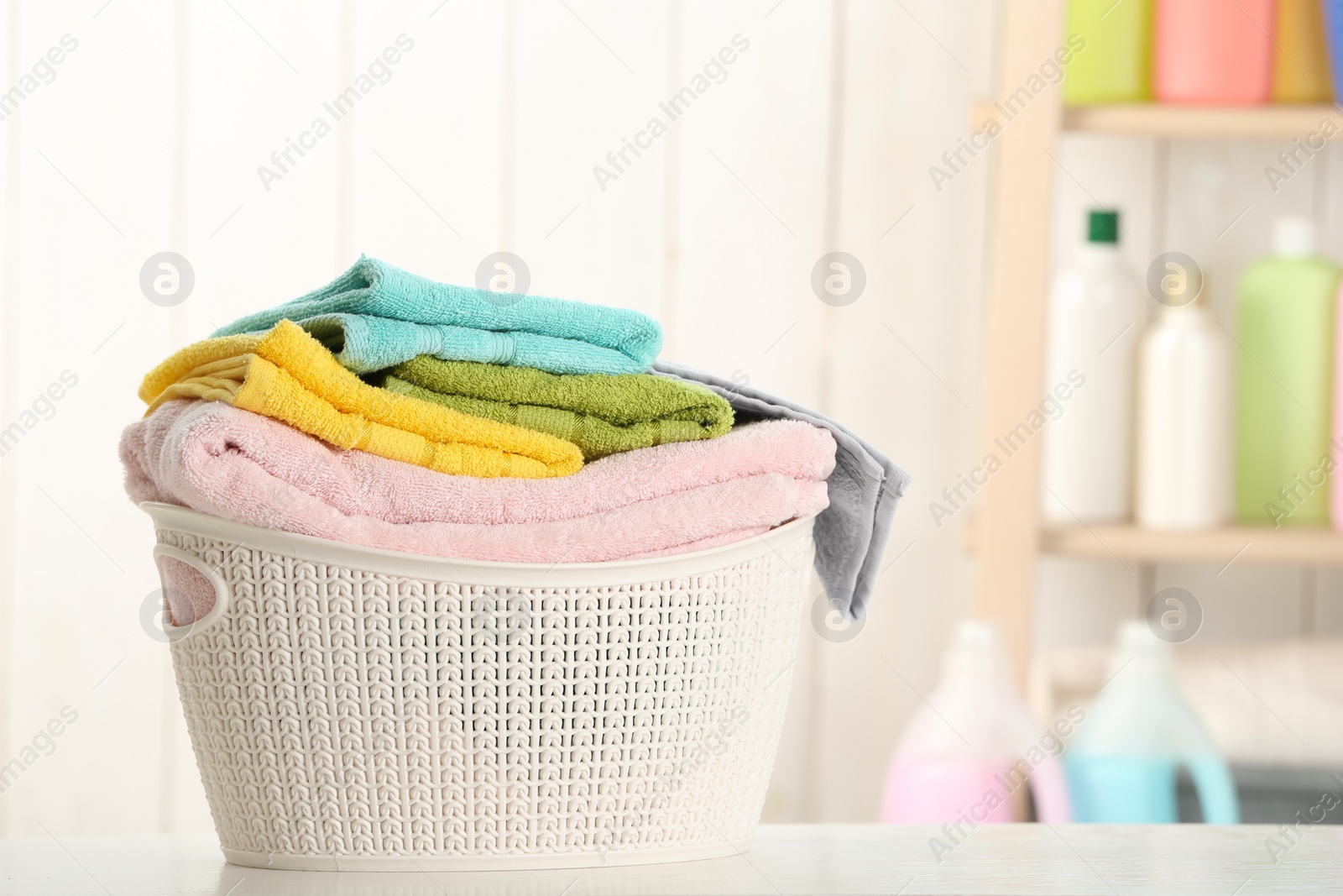 Photo of Basket with clean laundry on table at home, space for text