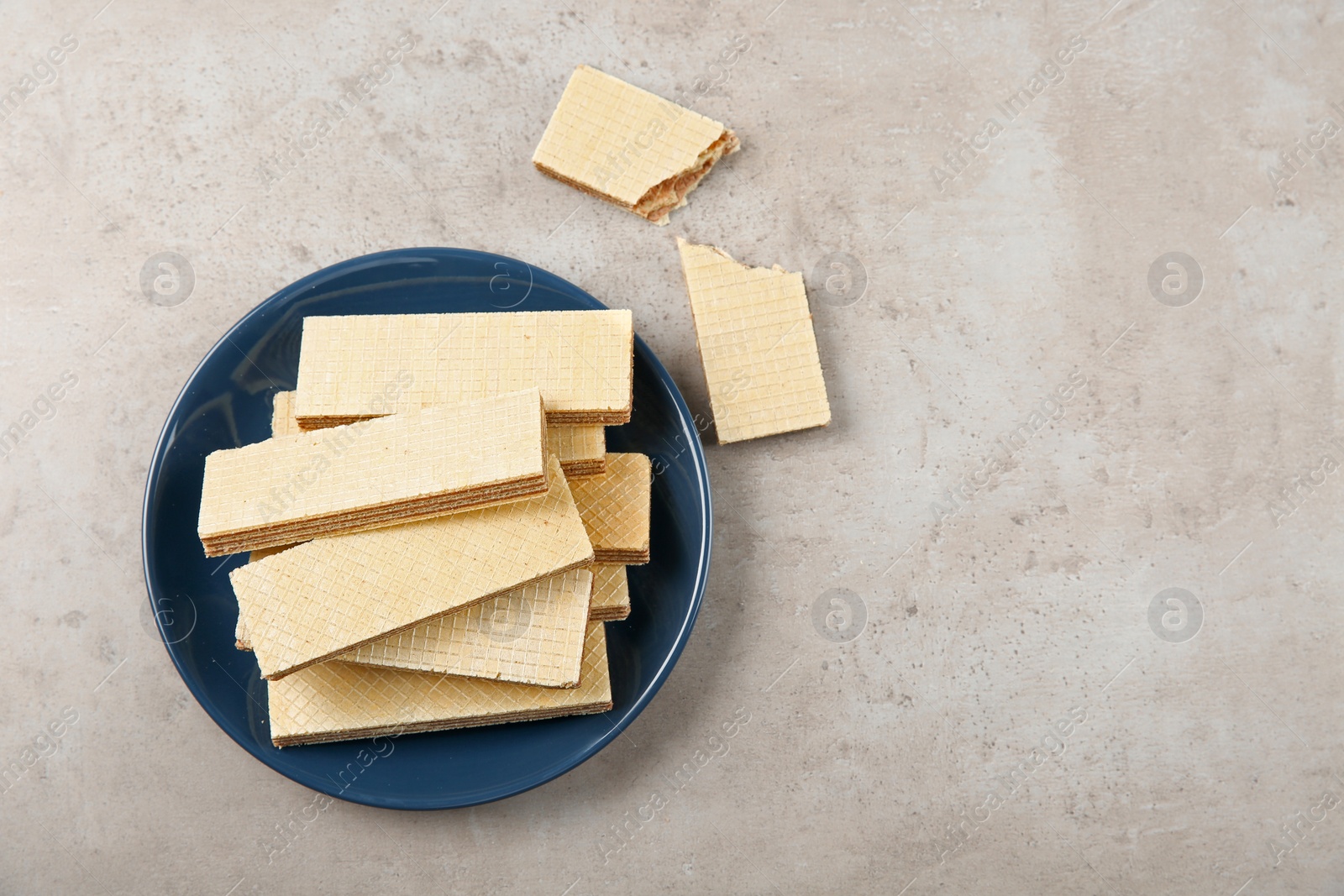 Photo of Plate of delicious wafers on grey stone background, top view. Space for text