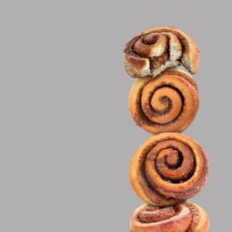 Cinnamon rolls balancing on grey background, space for text