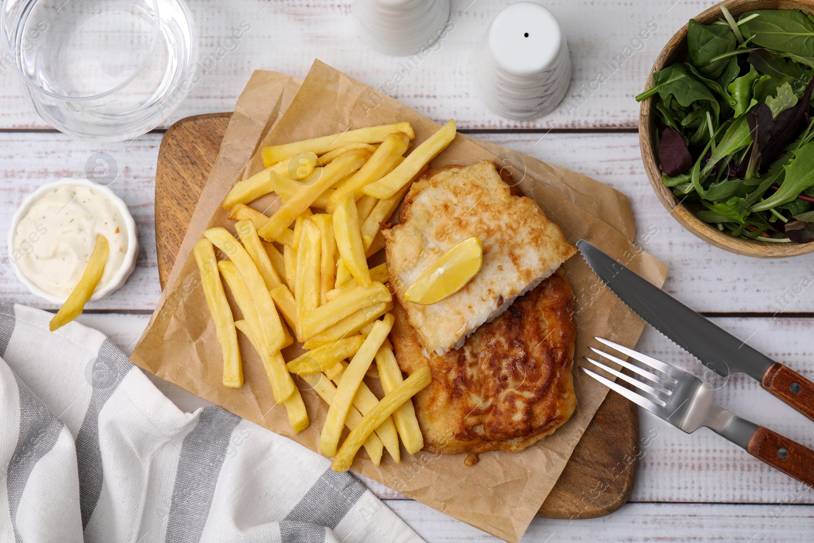 Photo of Tasty soda water battered fish, potato chips and lemon slice served on white wooden table, flat lay