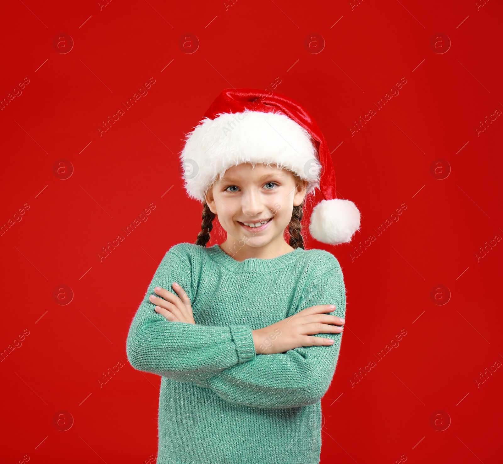 Image of Happy little child in Santa hat on red background. Christmas celebration