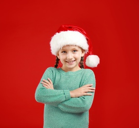 Image of Happy little child in Santa hat on red background. Christmas celebration