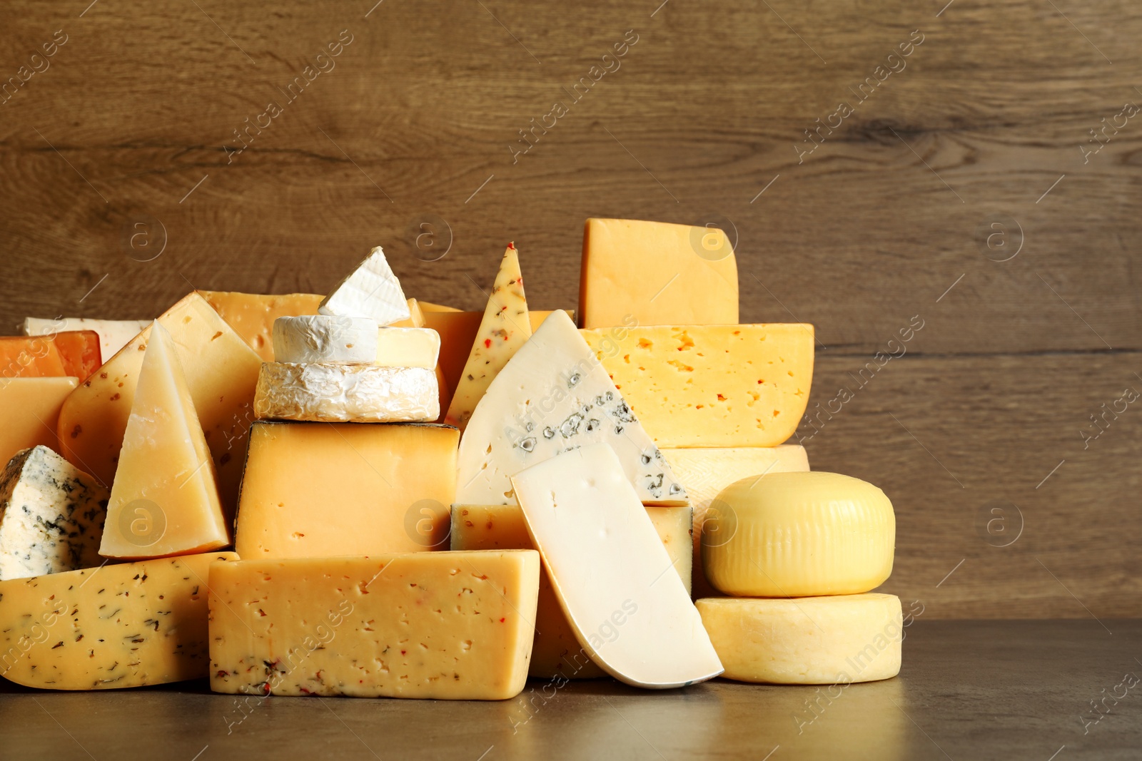 Photo of Different types of delicious cheese on table against wooden background