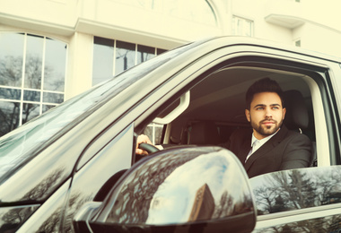 Handsome young man driving his modern car