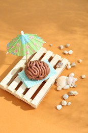 Photo of Brain made of plasticine on mini wooden sunbed under umbrella against orange background