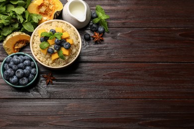 Photo of Flat lay composition with bowl of tasty quinoa porridge, pumpkin and blueberries on wooden table. Space for text