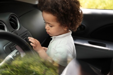 Photo of Little African-American girl alone inside car. Child in danger